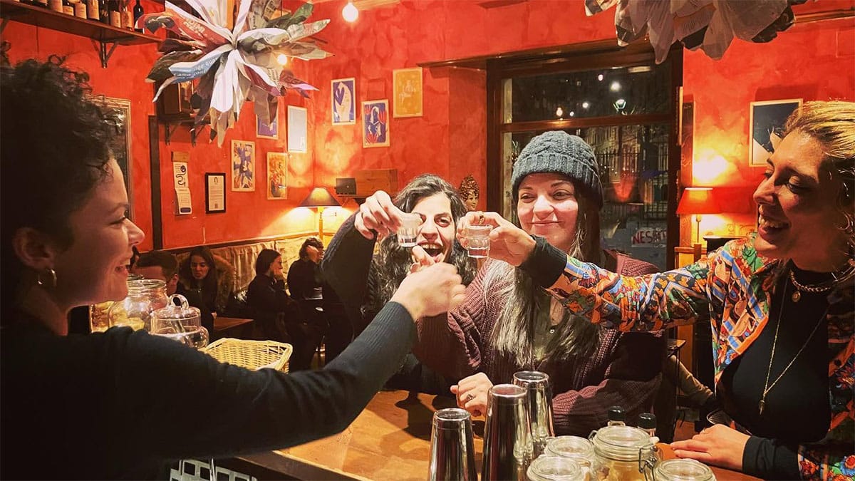 four ladies toasting with small shots in a dimly lit bar.