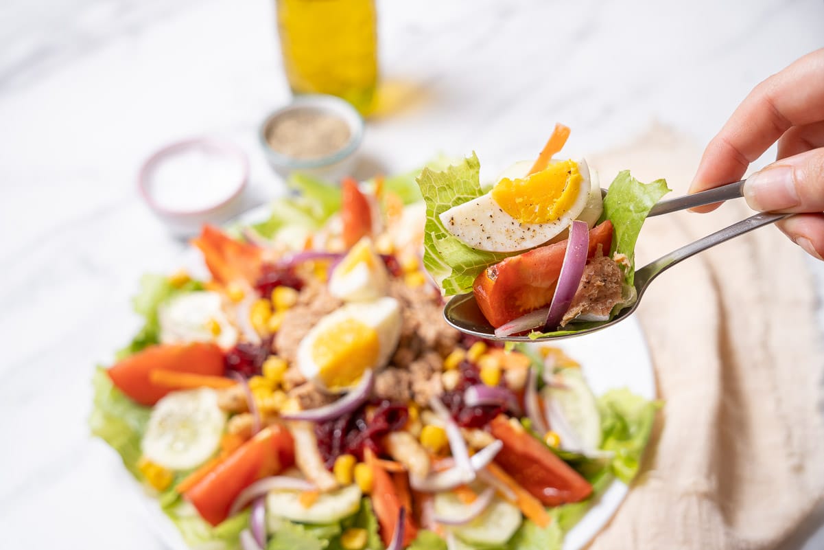 holding a spoonful of mixed salad with tuna.