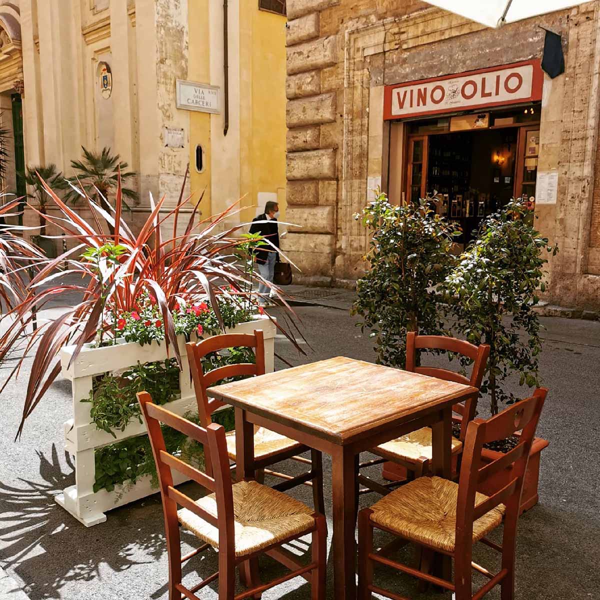 table with four chairs outside of a small wine shop.