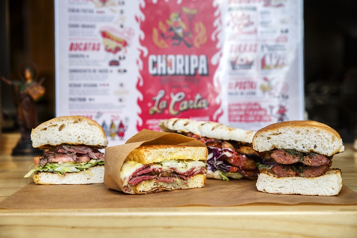 several sandwiches on brown paper on a cutting board.