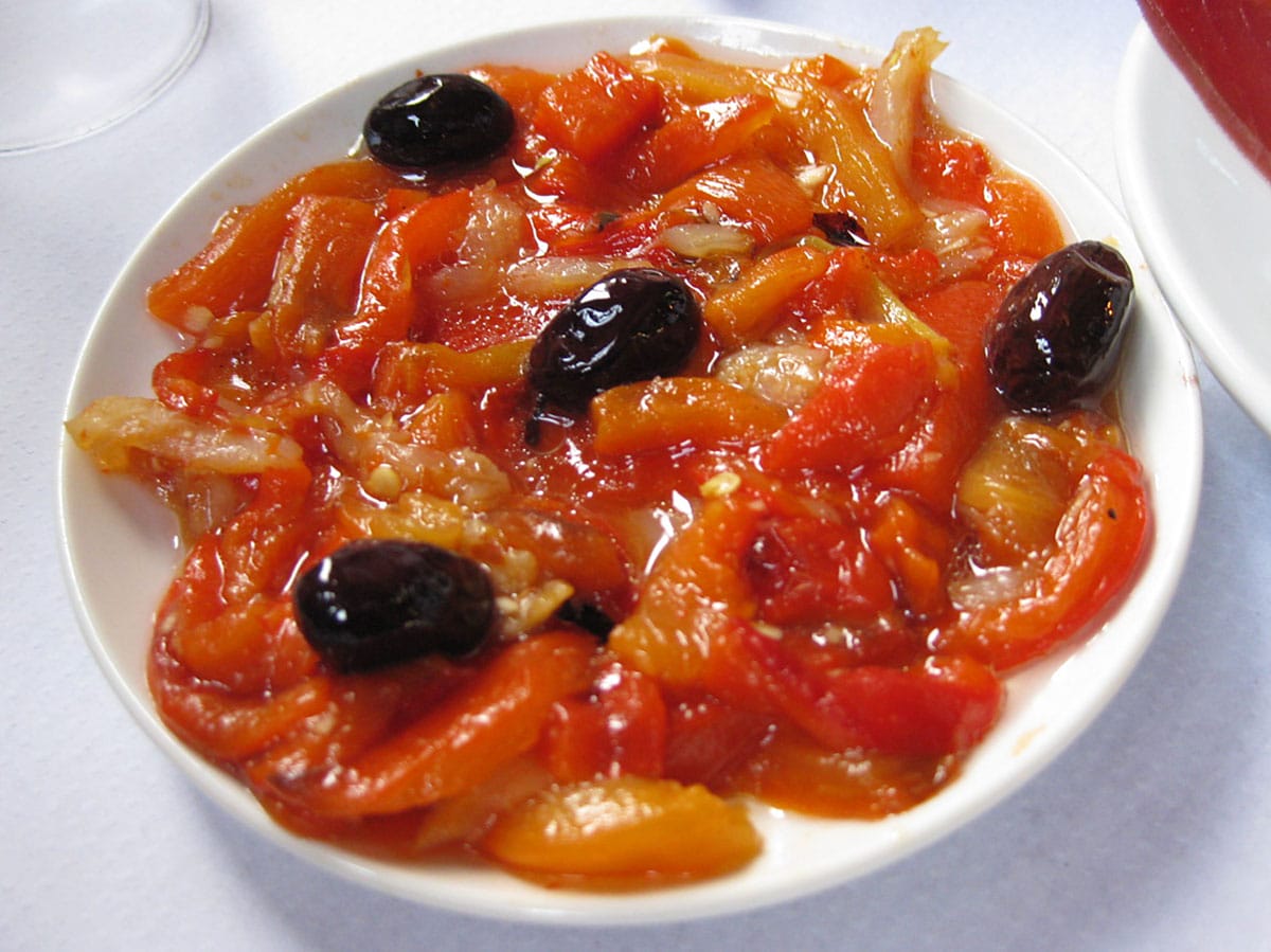 white plate filled with peppers, olives, and salted cod.