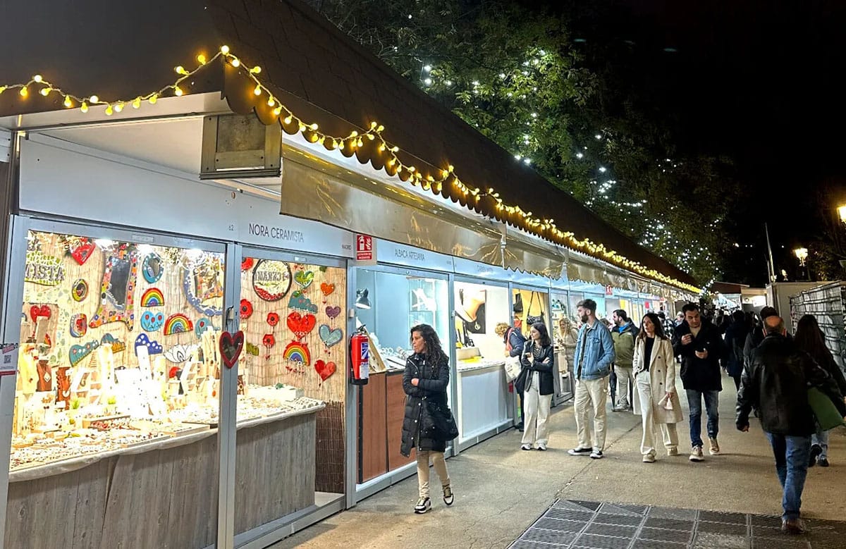 people walking down a street lined with craft vendors.