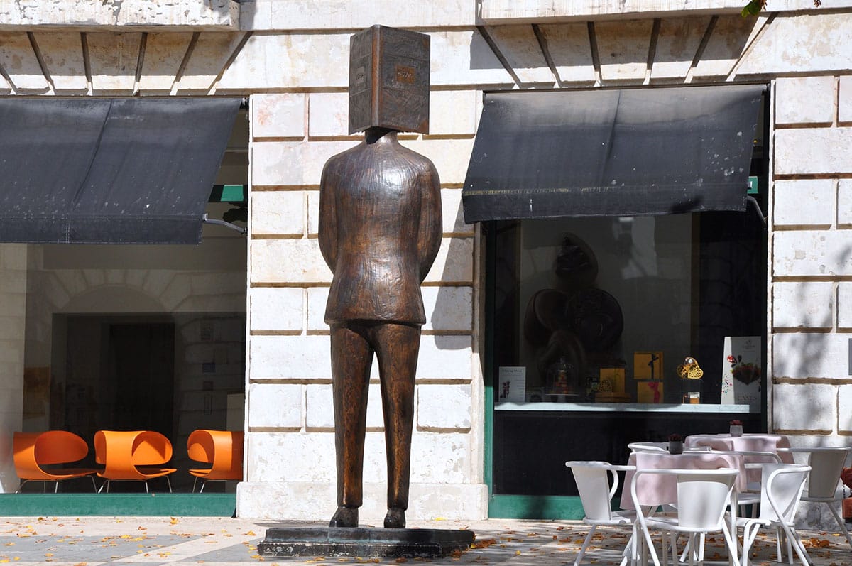 bronze statue of a man with an open book as his head.