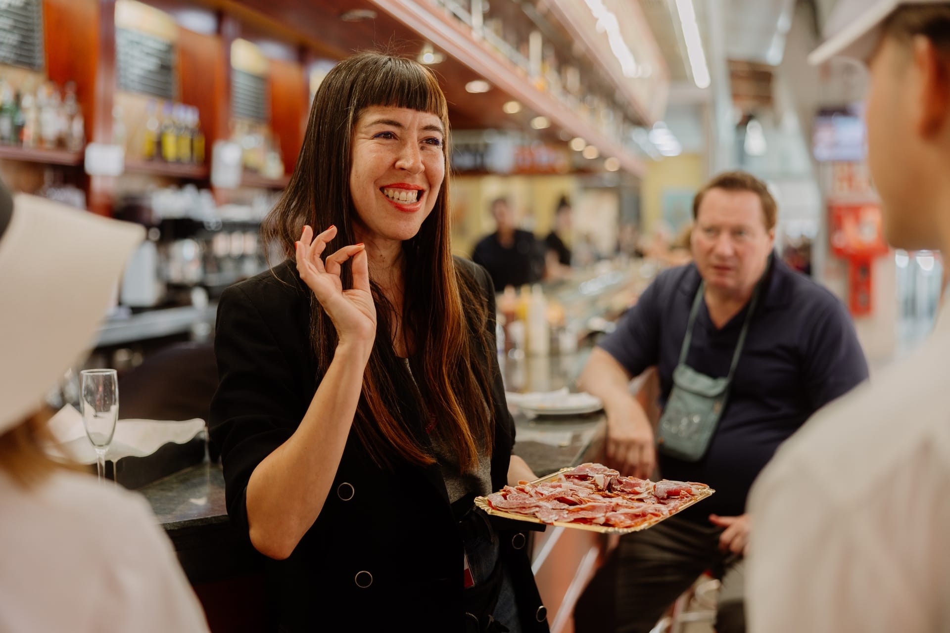 tour guide telling guests about jamón in a food market.