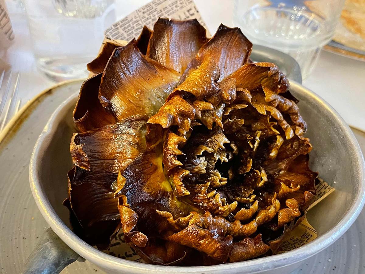 large fried artichoke in a white bowl.