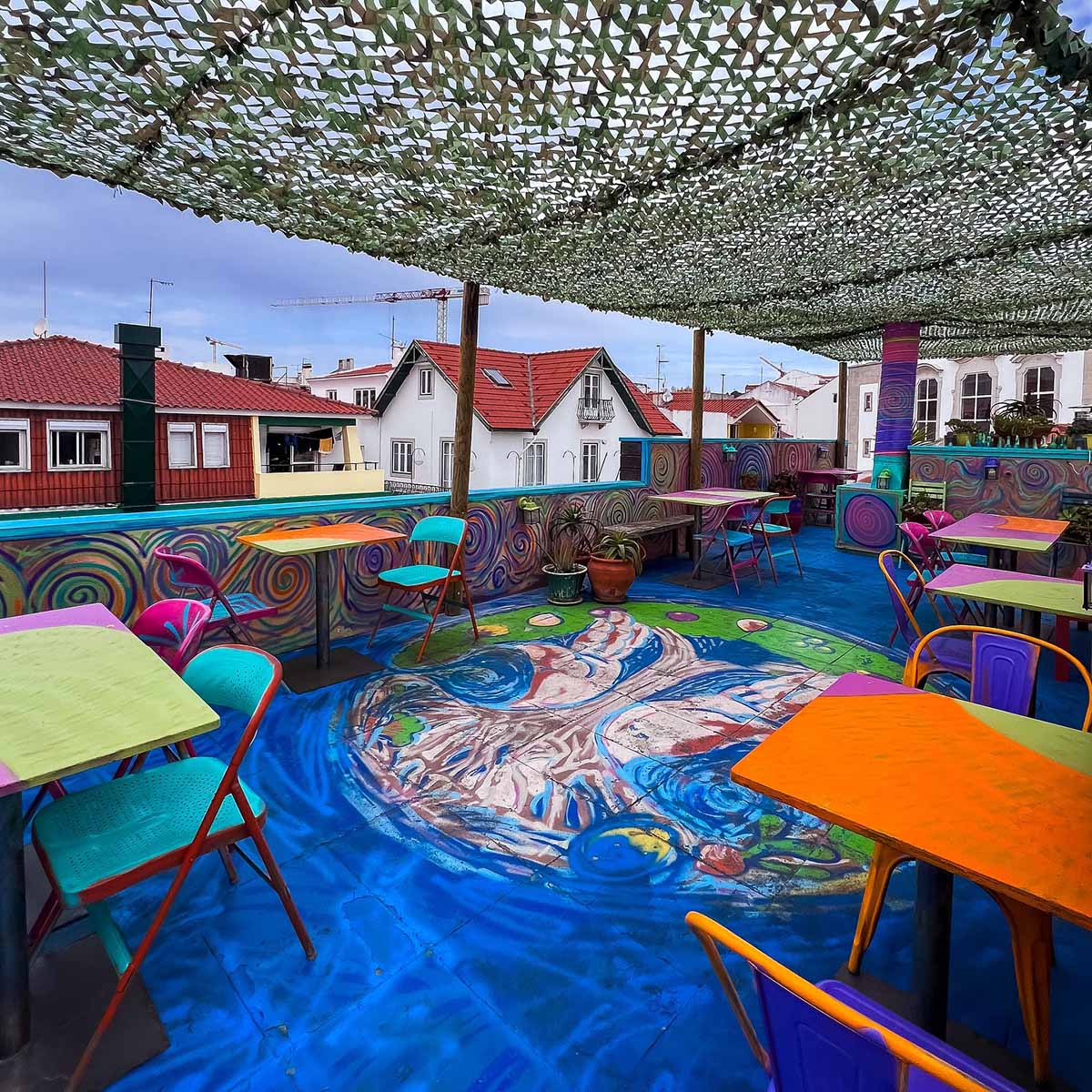 colorful painted rooftop under a canopy with tables and chairs set up.