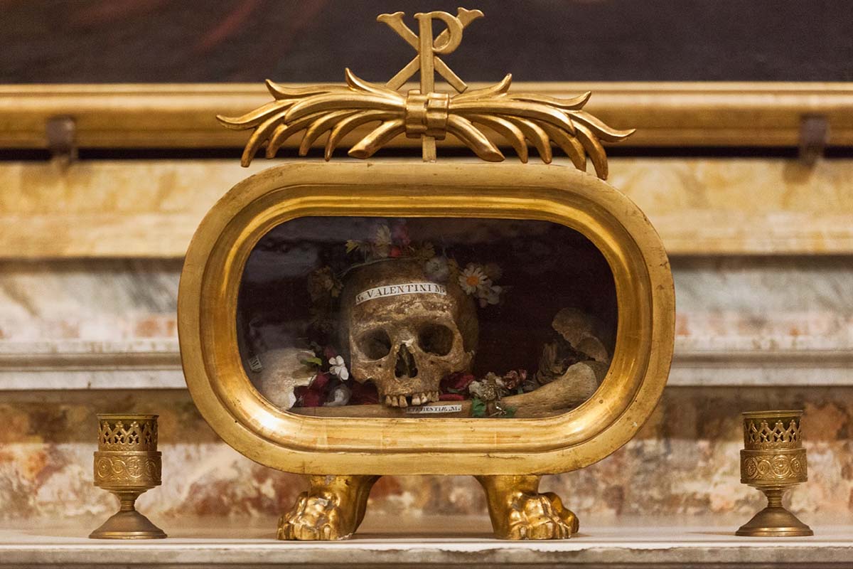 golden box with a flower-crowned skull and bones inside.