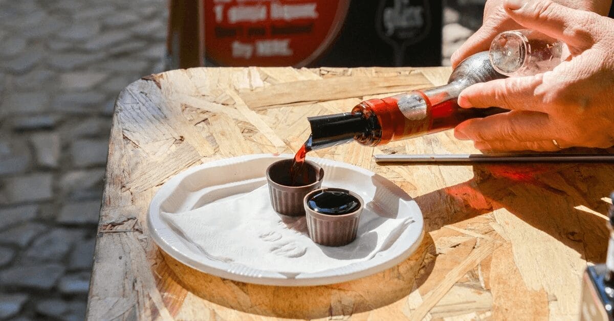 person pouring cherry liqueur into chocolate cups.
