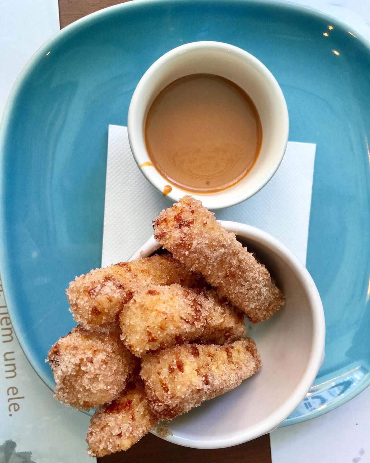 gluten free churros in a small white bowl with a cup of coffee.