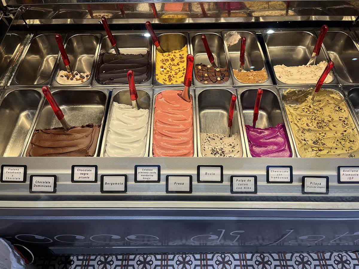 two rows of metal bins of gelato in different flavors.
