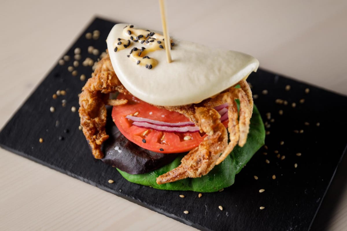 bao bun filled with soft shell crab, lettuce, onion, and tomato.