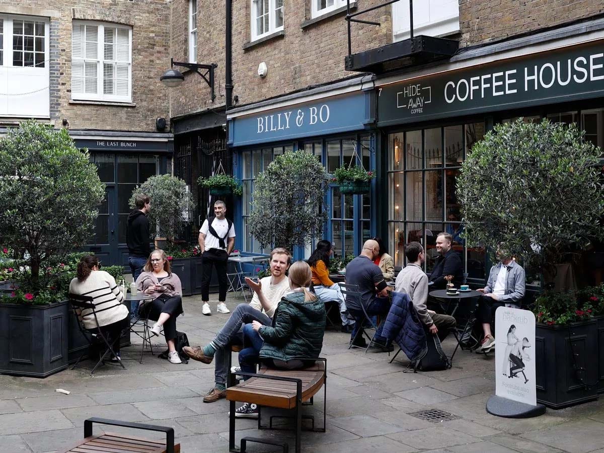 people having coffee at tables outside of a coffee shop.