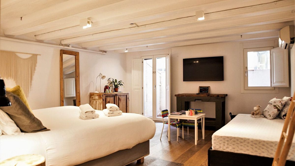 hotel room with two beds, a door, and a TV.