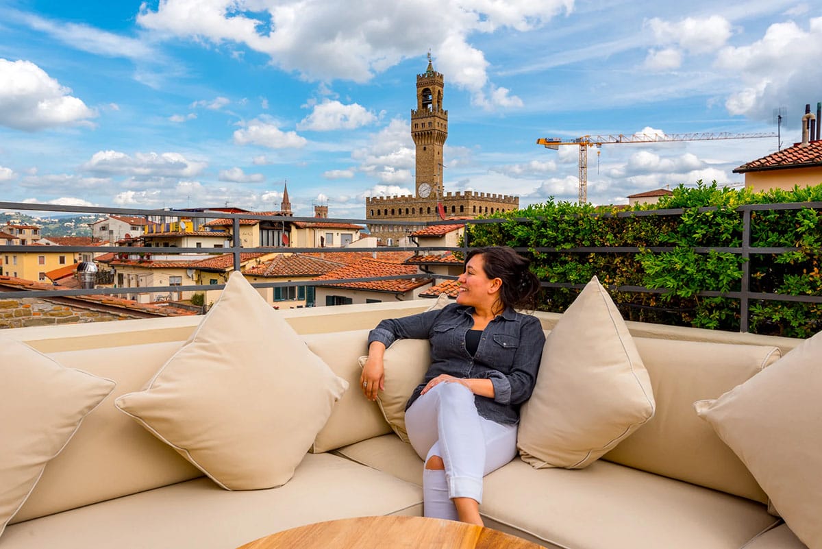 woman sitting on an outdoor couch on a rooftop overlooking Florence.