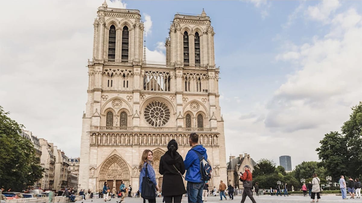 group of three tourists admiring the exterior of Notre Dame cathedral in Paris.