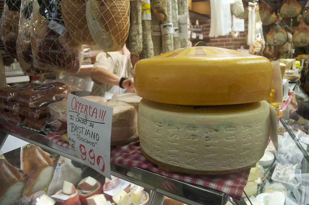 large wheels of Italian cheese on a counter at a market.
