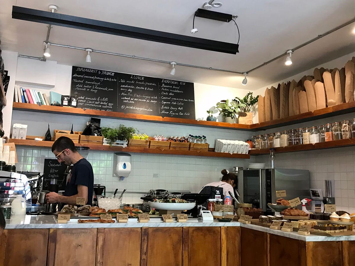baristas working at a counter with pastries and other food laid out.