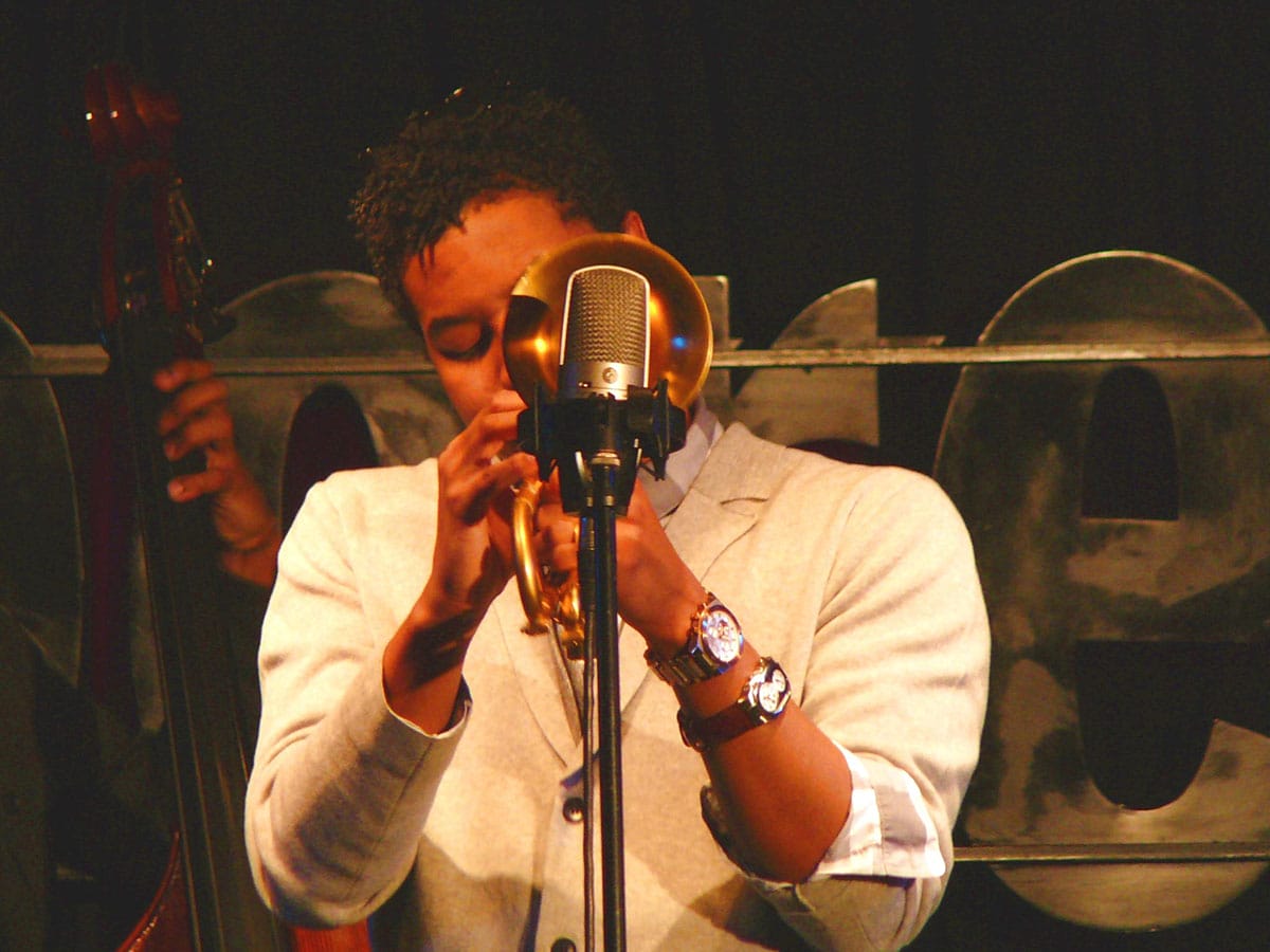 jazz trumpeter playing near a microphone on stage.