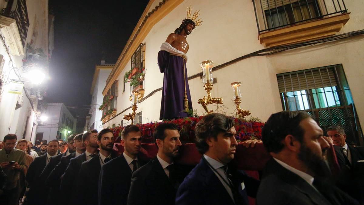 men in suits carrying a float of Jesus in a purple robe.