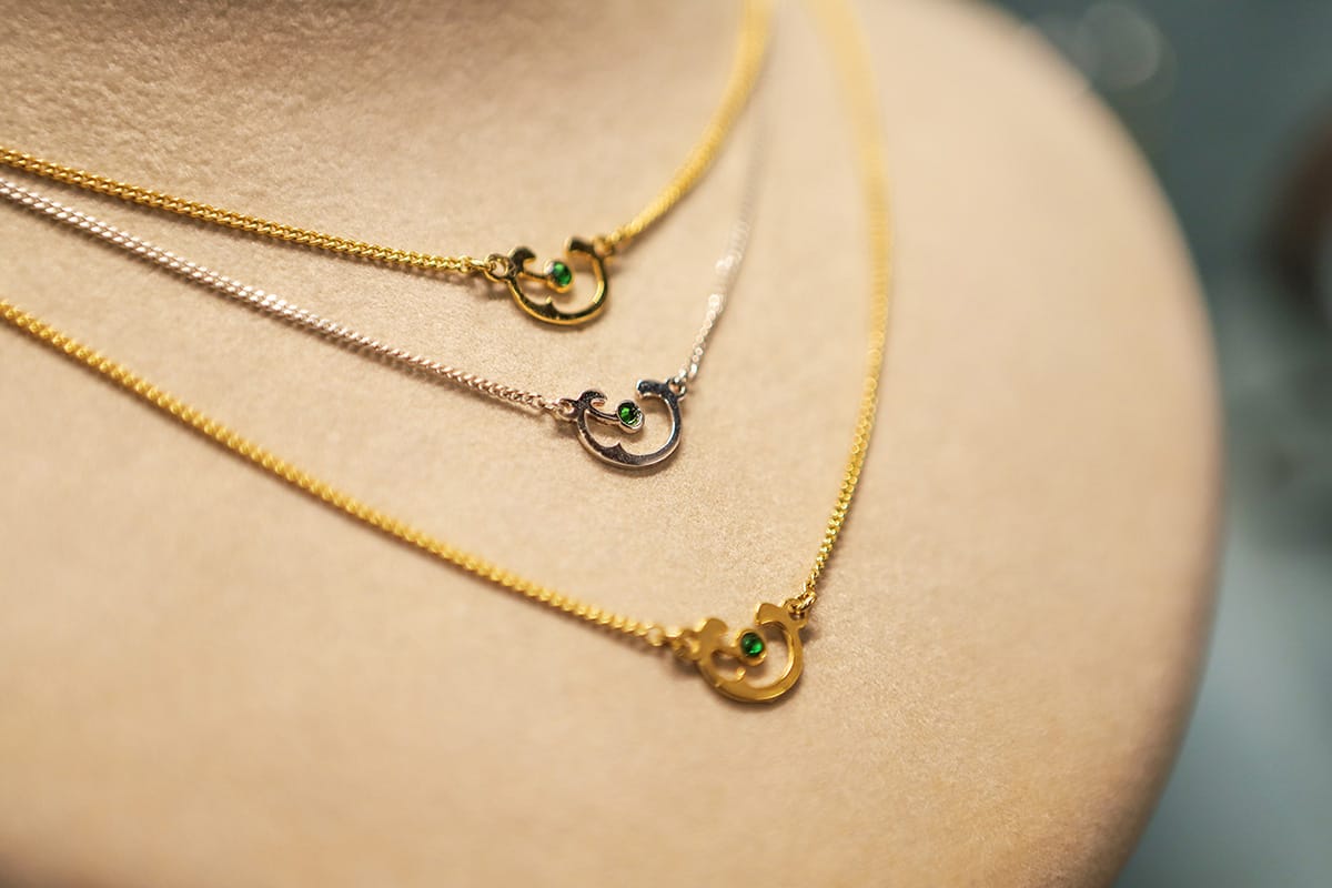 two gold and one silver necklaces on a mannequin.