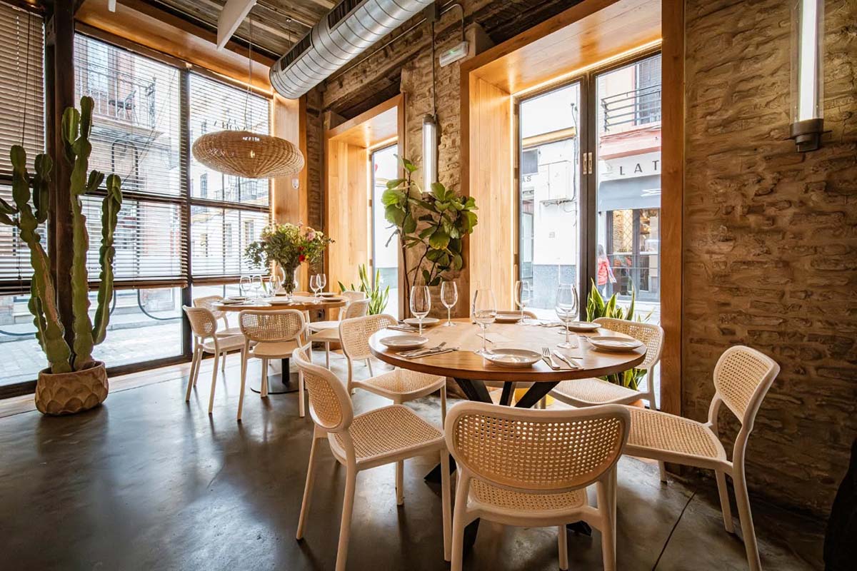 tables and chairs in a brick-walled restaurant with large windows.