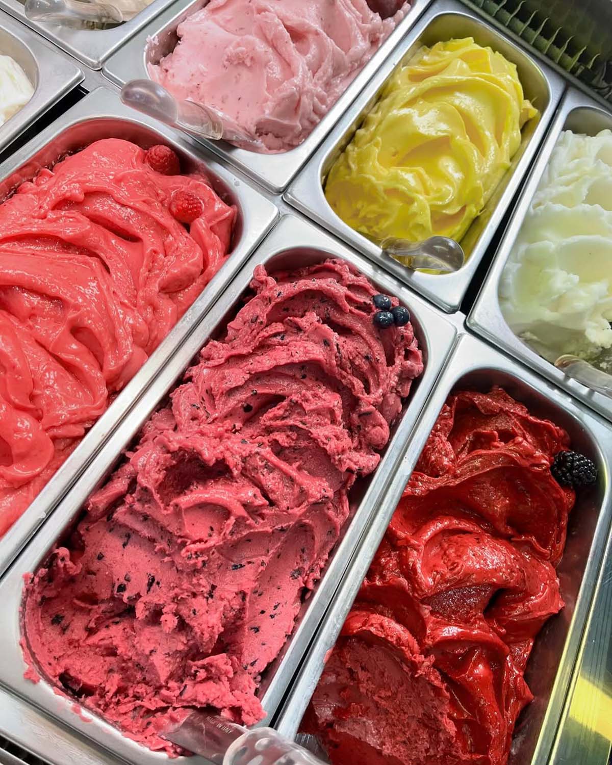 two rows of stainless steel tubs of colorful homemade fruit gelato.