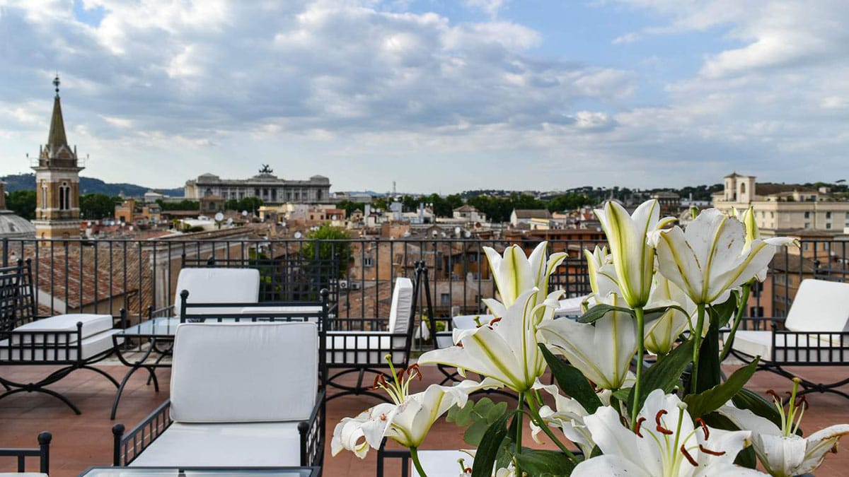 metal chairs with white cushions and a white lily flower arrangement on a rooftop restaurant.