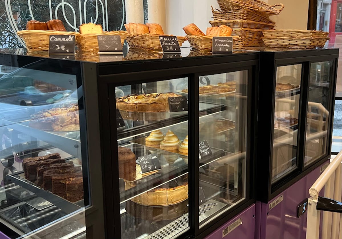 pastries on glass shelves in a case and breads in baskets on top.