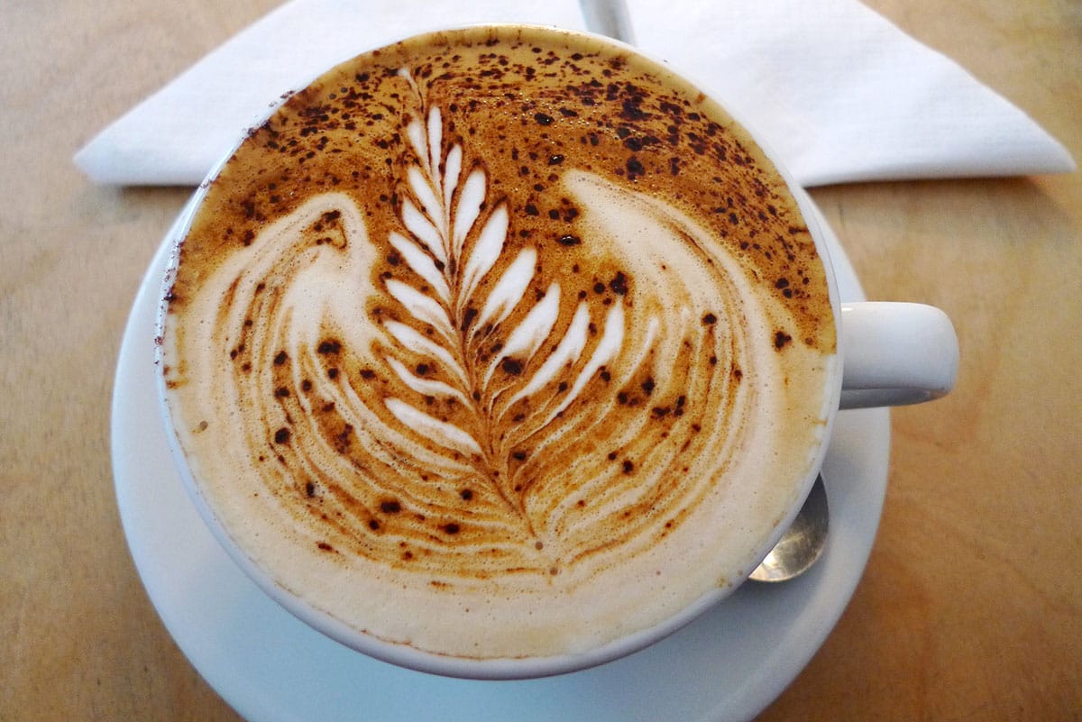 latte in a white mug with feathered steamed milk on top.
