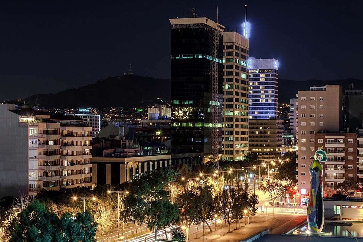 skyscrapers at night near a tree-lined street.