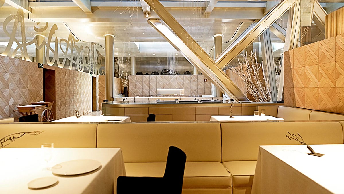 yellow booths and tables with modern tiles on the walls and tree branch decorations.