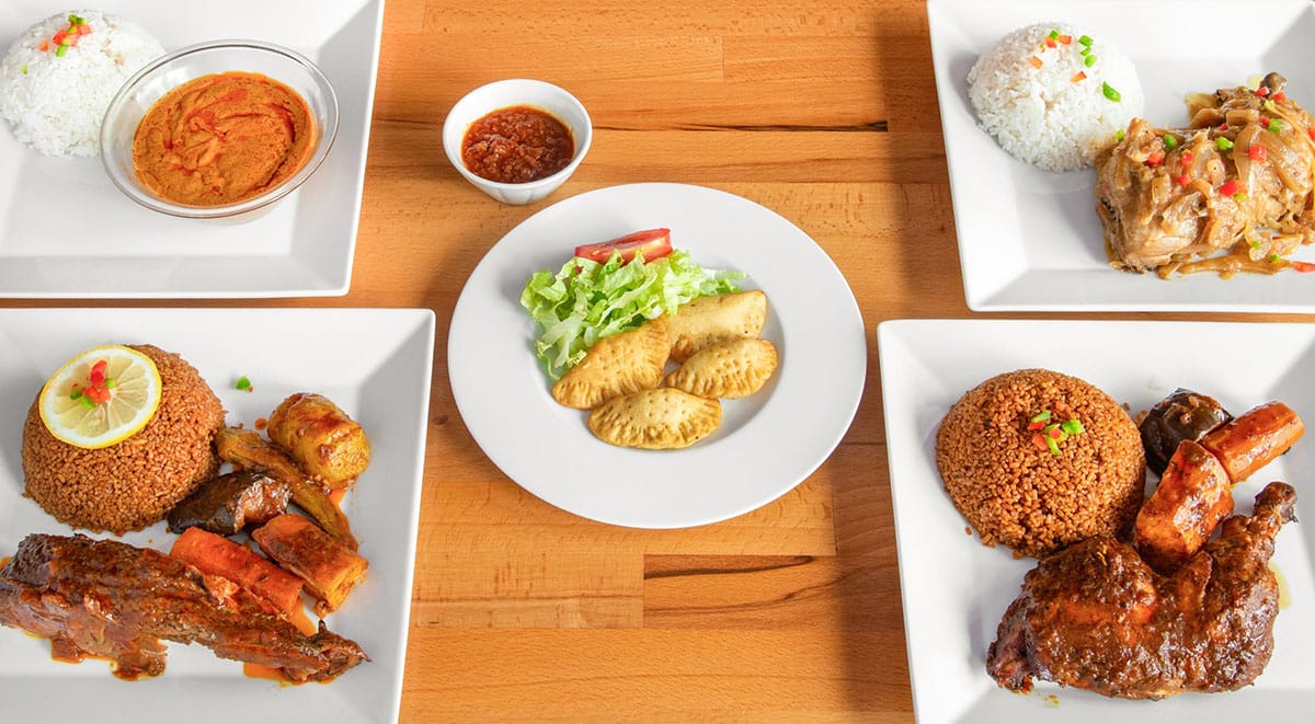 small white plates of African food on a wooden table.