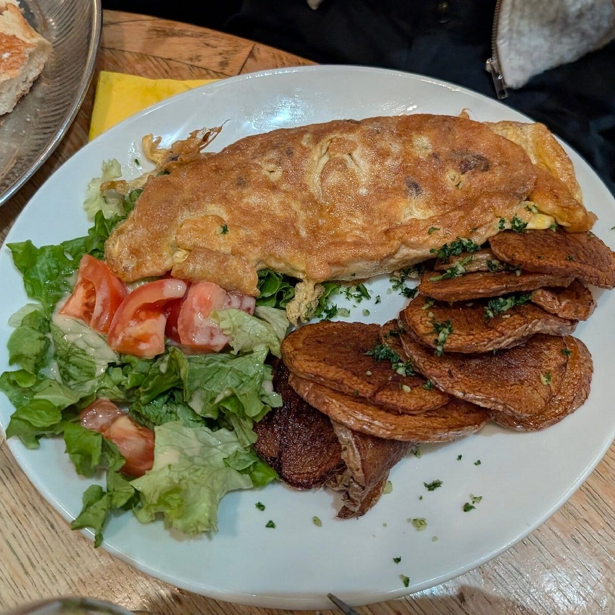crispy omelet with fried potatoes, tomatoes, and lettuce on the side.