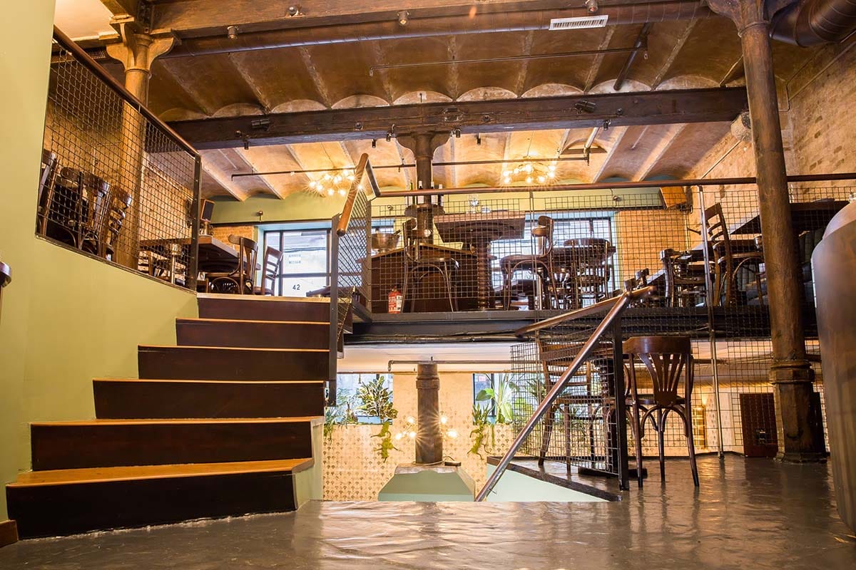 multi-level restaurant with metal railings and windows with a high ceiling.