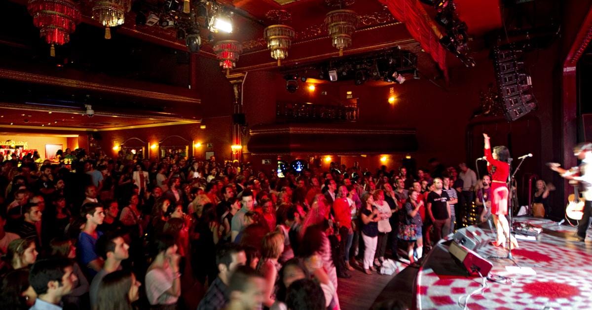 performers onstage with the audience in a historic music hall.