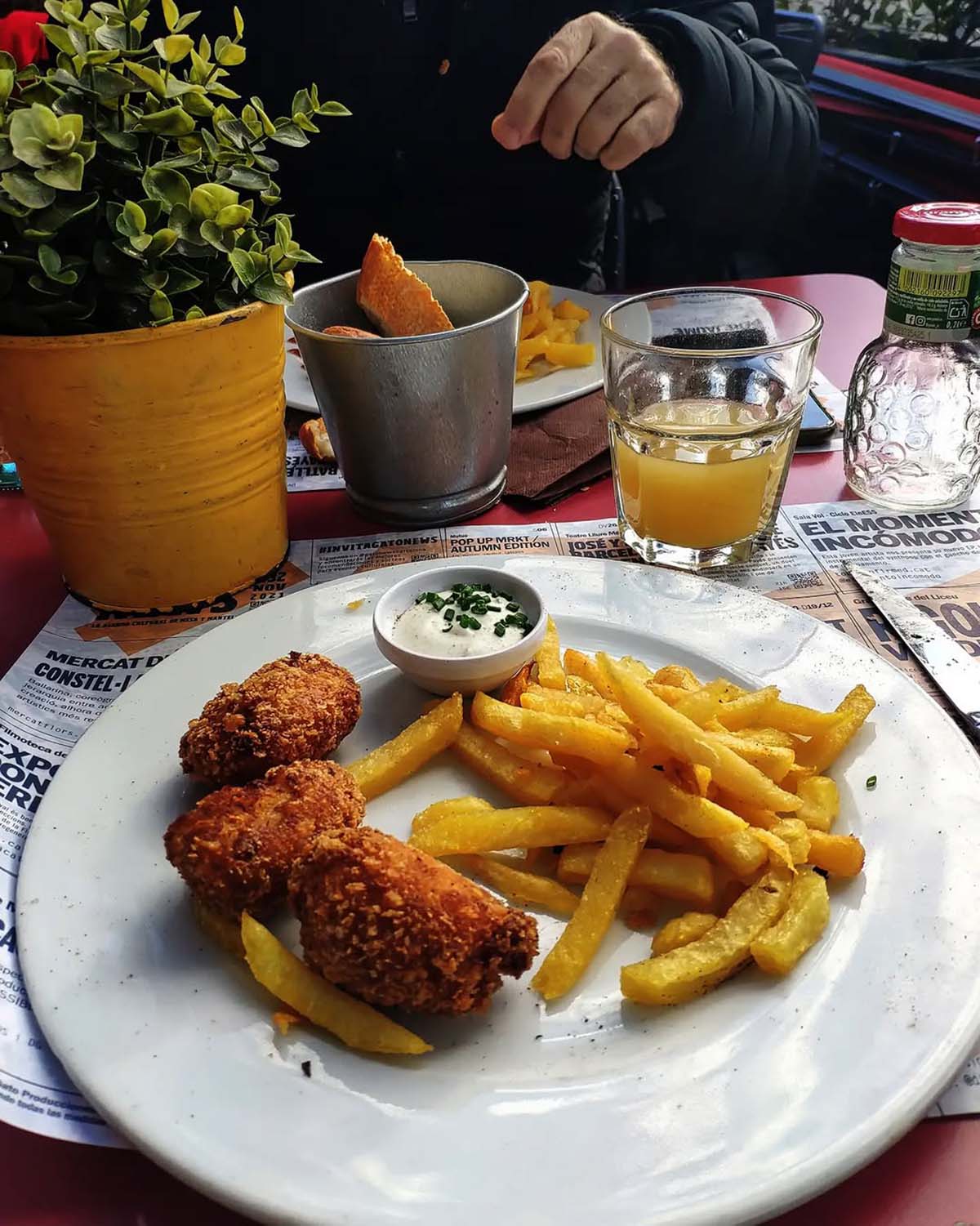 plate of croquettes and fries with a dipping sauce on a table.