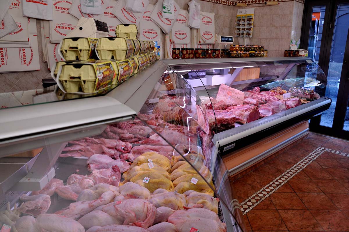 glass cases of meat and offal in a tile-floored butcher shop.