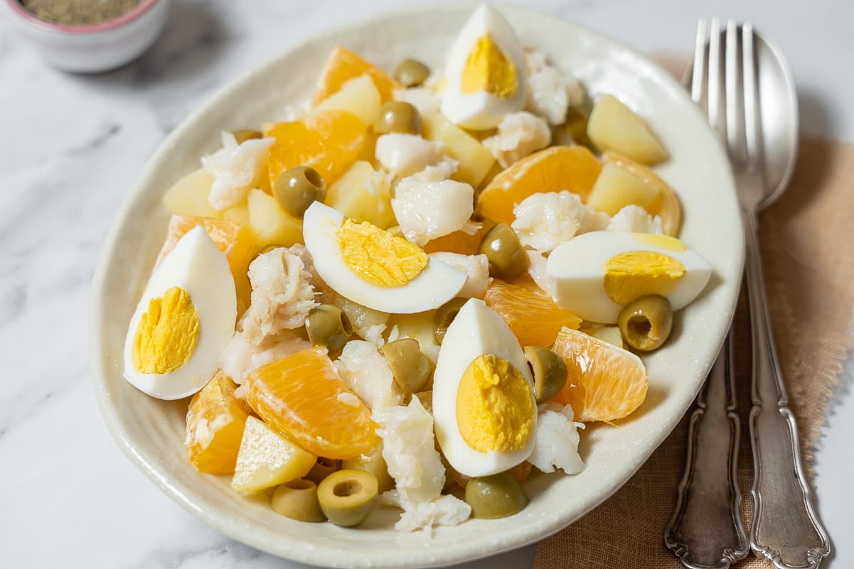 white platter of tuna, egg, and orange salad topped with egg.
