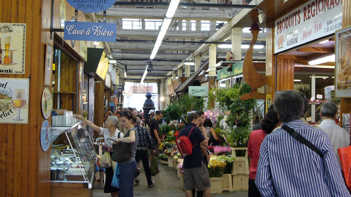 busy French indoor market setting flowers and food.