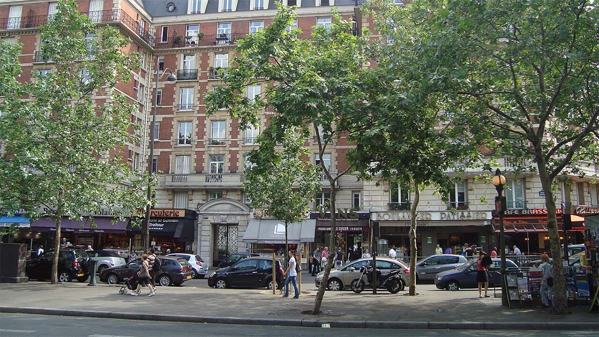 exterior of a Parisian food market on a tree-lined busy street.