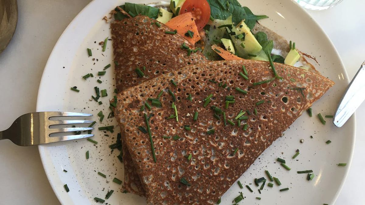 folded vegan galette with a savory vegetable filling on a white plate.
