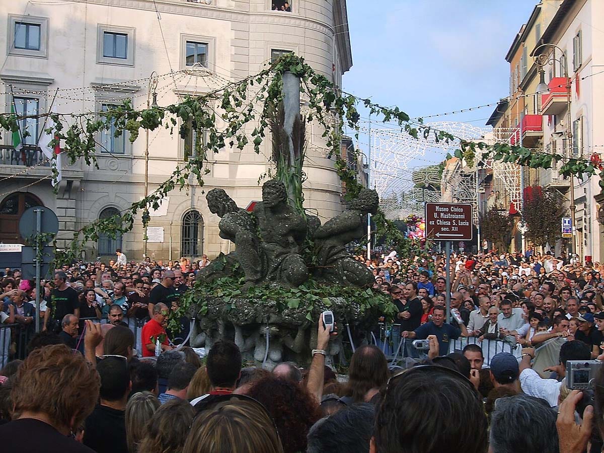 ornate dark stone fountain in the center of a crowded square.