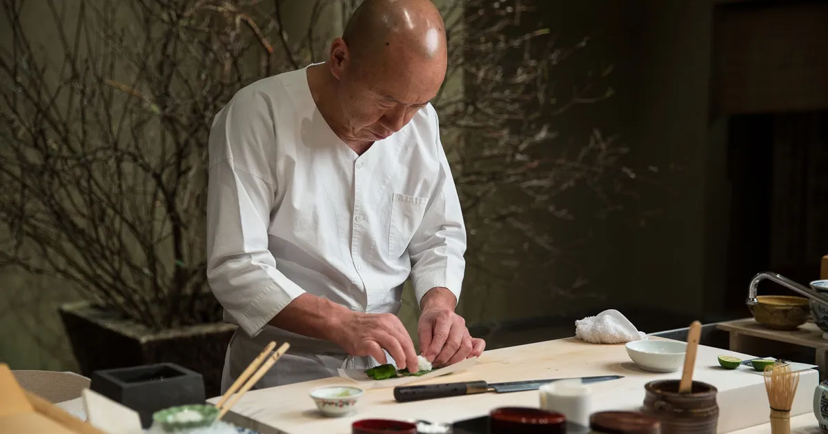 chef making sushi on a wooden block.