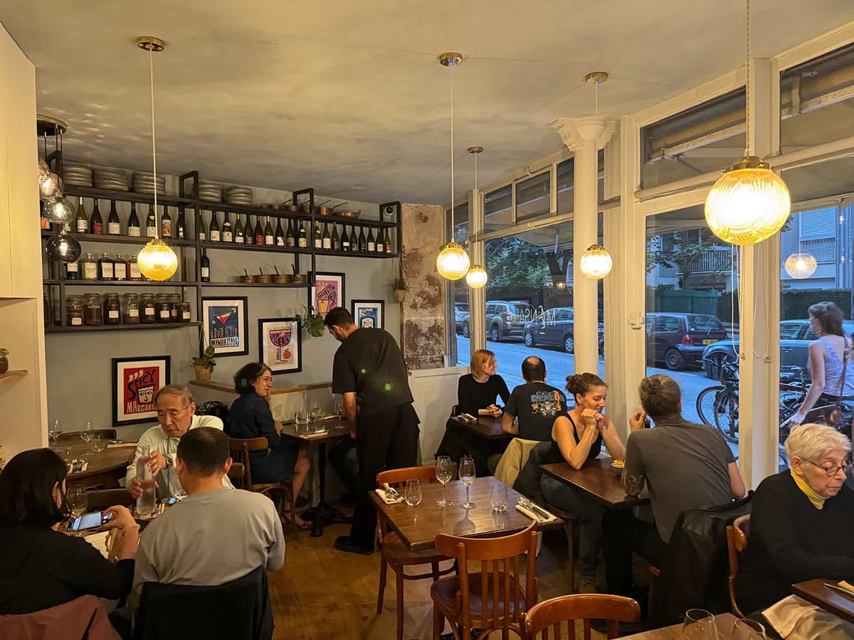 small wooden tables of people eating in a Parisian cafe.