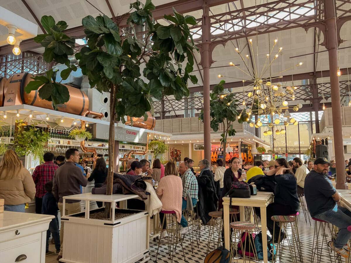 tables and chairs of people eating at an indoor food market.