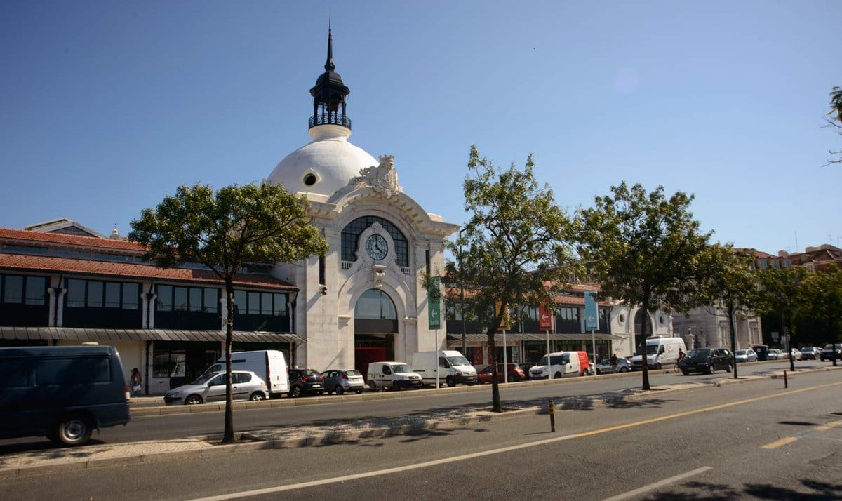 white domed building with large glass windows and trees growing in front.