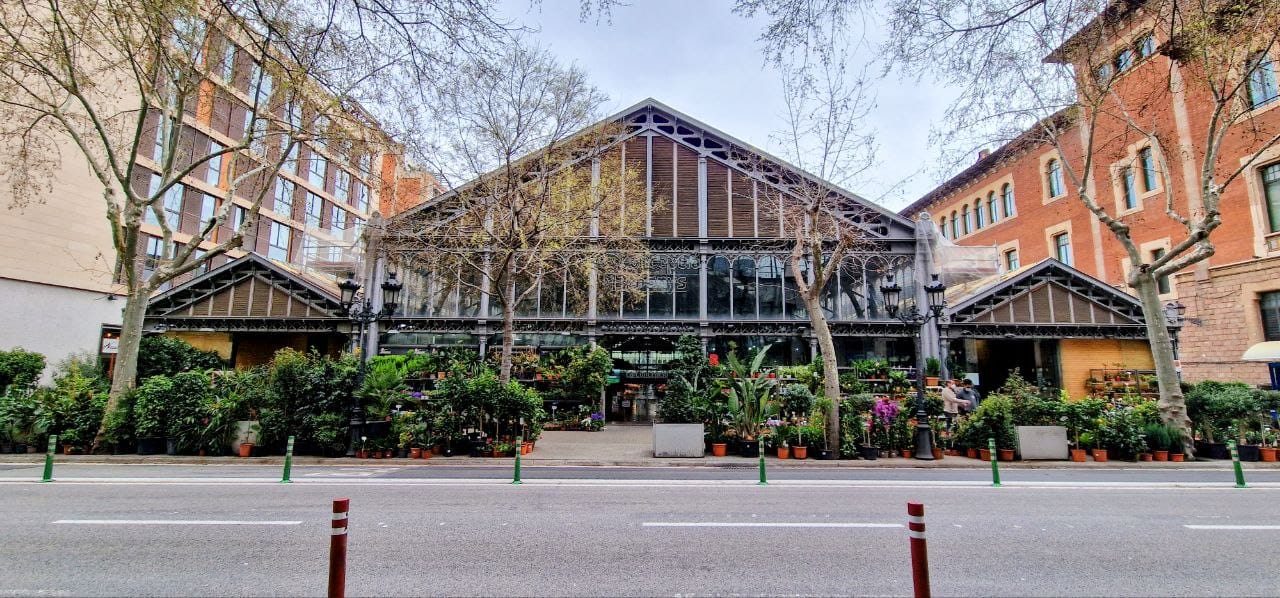 large building with glass windows and many plants outside.