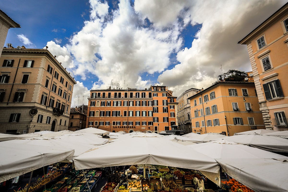 Mercato Campo de&rsquo; Fiori in a square in Rome surrounded by tall buildings.