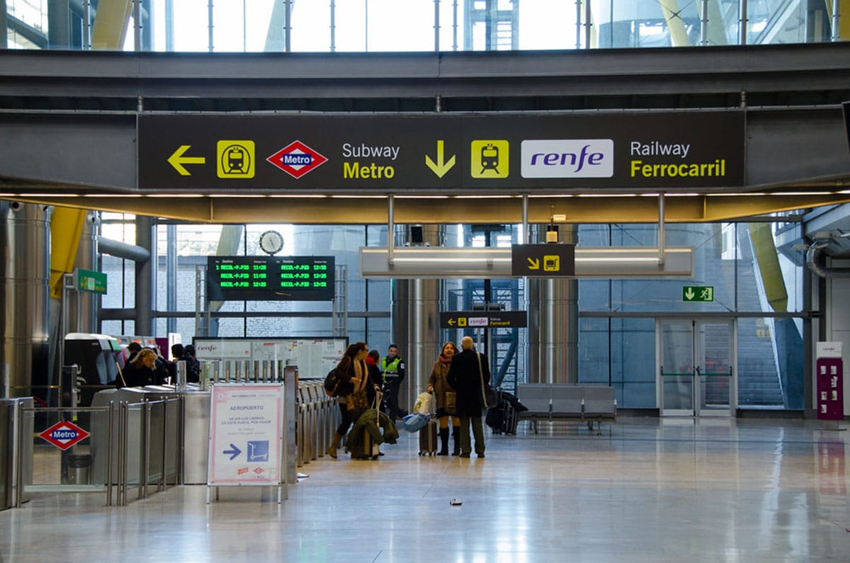 people in the Madrid airport following the signs to the metro and rail stations.