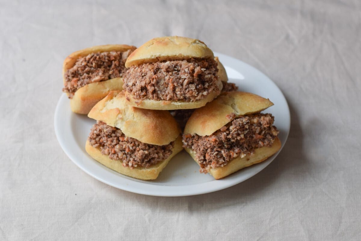 a white platter of montadito de pring&aacute; sandwiches.